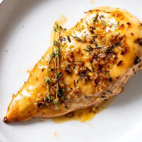 A close-up of Honey Dijon Chicken Skillet showing thick, tangy sauce coating juicy chicken, perfect over mashed potatoes.  