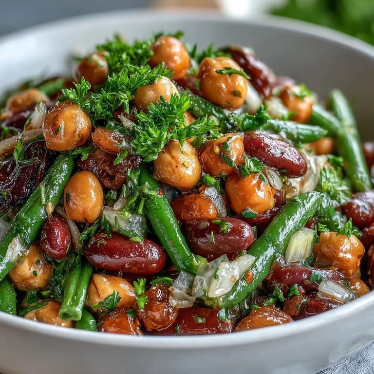 Overhead view of the Three-Bean Salad, highlighting the colorful medley of beans, celery slices, and fresh herbs in a glossy apple cider vinegar dressing.