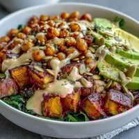 Golden roasted sweet potatoes and crispy chickpeas piled high in a white bowl for a healthy vegetarian meal.