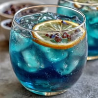 A vibrant blue lemonade transforms to purple when citrus meets butterfly pea flower infusion in this magical drink.